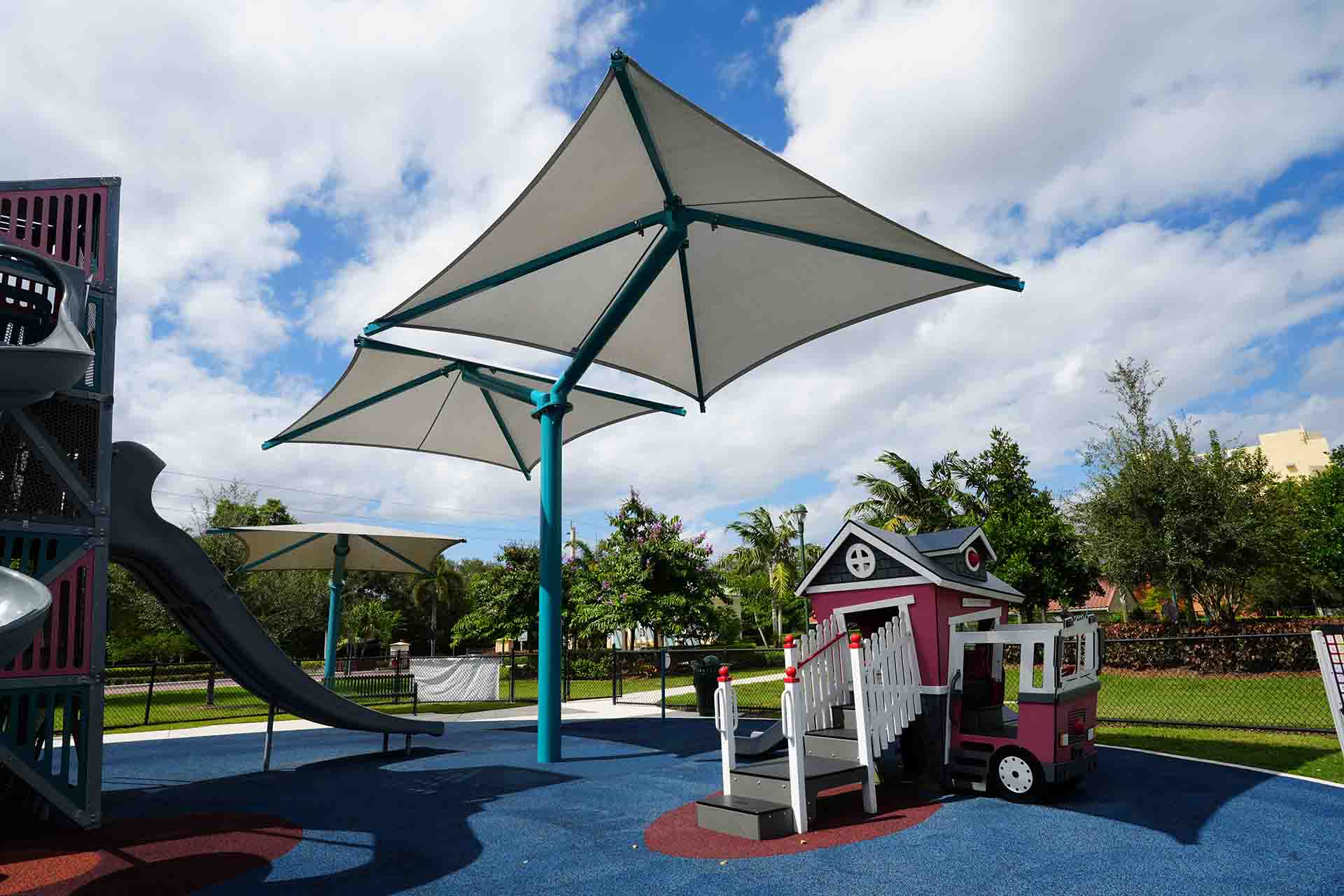 Shaded playground with slides and play structures in Weston.