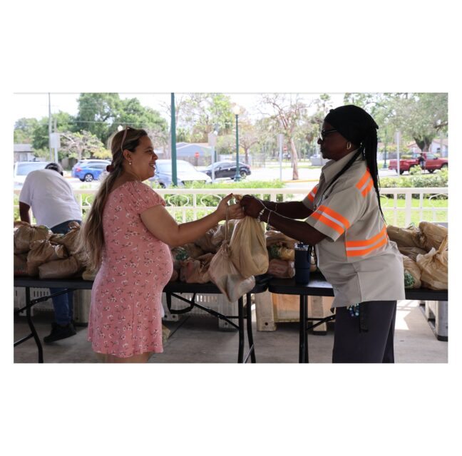 Woman receiving bags of groceries at a Farm Share distribution