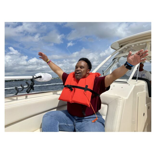 Participant in a life vest raising both arms aboard a Freedom Waters Foundation boat