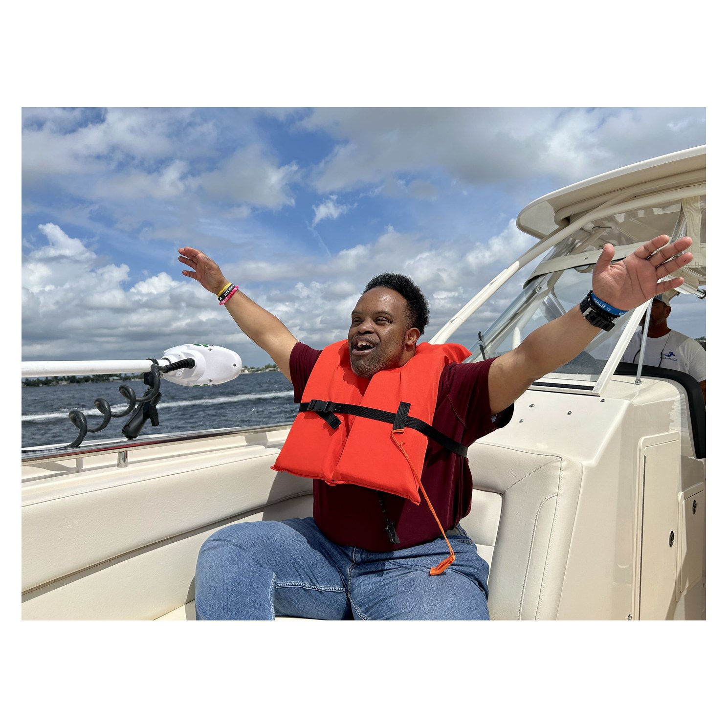 Participant in a life vest raising both arms aboard a Freedom Waters Foundation boat